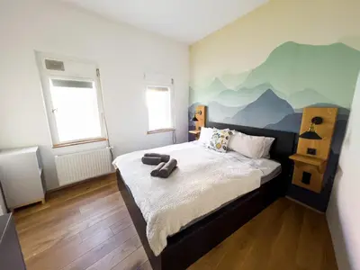 a bedroom with a bed with a mountain mural on the wall at FERN apartments in Maribor