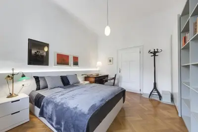 a white bedroom with a bed and a desk at City Center Apartment with Parking in Ljubljana