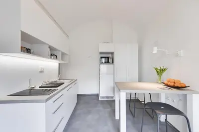 a white kitchen with a table and chairs at City Center Apartment with Parking in Ljubljana