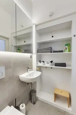 a white bathroom with a sink and a mirror at City Center Apartment with Parking in Ljubljana