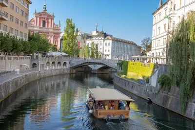a boat traveling down a river with a bridge at City Center Apartment with Parking in Ljubljana