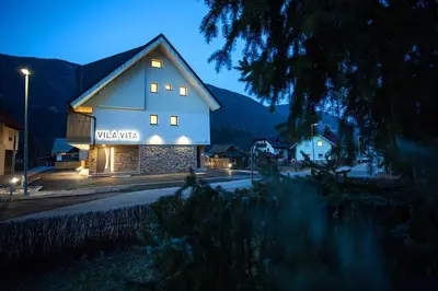 a building with a sign on the side of it at night at Vila Vita Apartments in Kranjska Gora