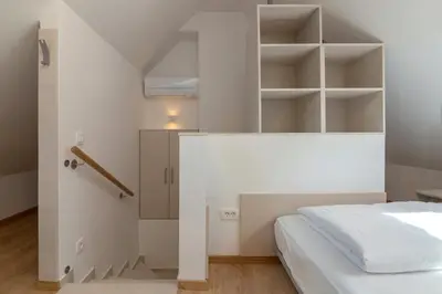 a bedroom with a white bed and shelves at Vila Vita Apartments in Kranjska Gora