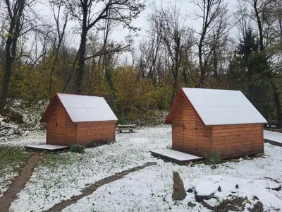 two small buildings with snow on them in a yard at Koča sredi gozda in Kanal