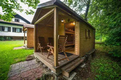 a small wooden cabin with a chair in a yard at Koča sredi gozda in Kanal