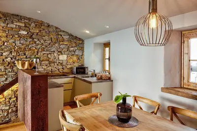 a kitchen and dining room with a table and a stone wall at Aldilà Art Rooms, Apartment and Vacation House in Šmartno