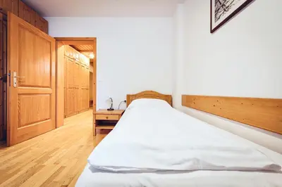 a bedroom with a large bed and a wooden door at Pohorje Village Wellbeing Resort - Family Apartments Bolfenk in Pohorje
