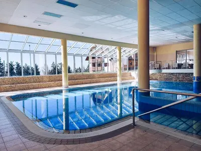 a large pool in a building with blue water at Pohorje Village Wellbeing Resort - Family Apartments Bolfenk in Pohorje