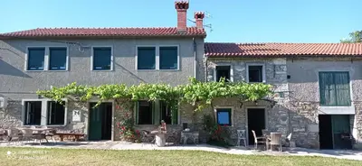a house with a person sitting in front of it at Barbara`s Village House in Ilirska Bistrica