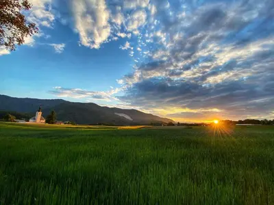 a field of green grass with the sunset in the background at Luxury holiday home near Lake Bled & the Alps in Kropa