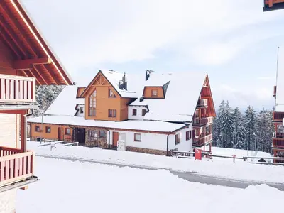 a winter view of a village in the snow at Pohorje Village Wellbeing Resort - Forest Apartments Videc in Pohorje