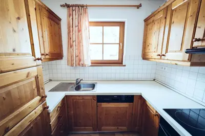 a kitchen with wooden cabinets and a sink and a window at Pohorje Village Wellbeing Resort - Forest Apartments Videc in Pohorje