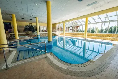 a large swimming pool in a building with yellow columns at Pohorje Village Wellbeing Resort - Forest Apartments Videc in Pohorje