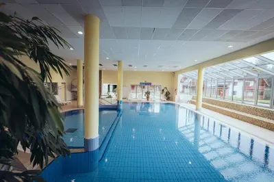 a large swimming pool with blue tiles in a building at Pohorje Village Wellbeing Resort - Forest Apartments Videc in Pohorje