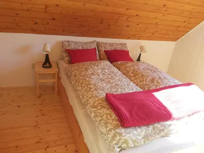 a large bed with red pillows in a bedroom at Alpine Village Home in Bohinj