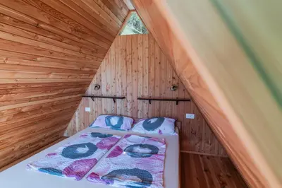 a bed in a wooden room with a roof at Glamping Tinka in Tolmin