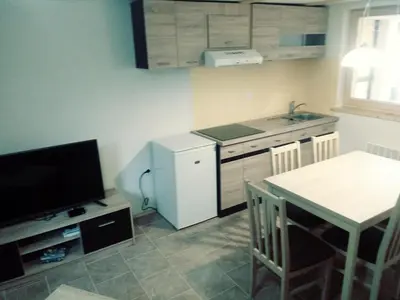 a kitchen with a table and a small kitchen with a television at apartma HIŠKA KOROŠEC in Bohinj