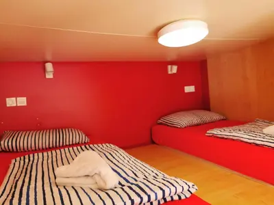 two beds in a room with a red wall at Cube studio by the river (with free bike rental) in Ljubljana