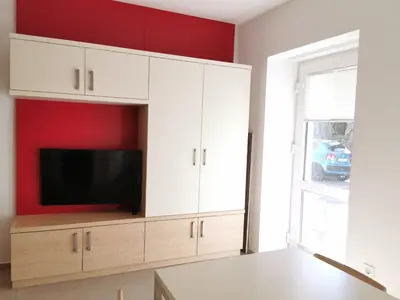 a living room with white cabinets and a flat screen tv at Cube studio by the river (with free bike rental) in Ljubljana