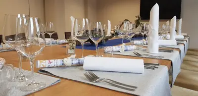 a long wooden table with wine glasses and napkins at Hotel Špica Laško in Laško