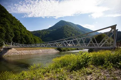 a bridge over a river with a mountain in the background at Hotel Špica Laško in Laško