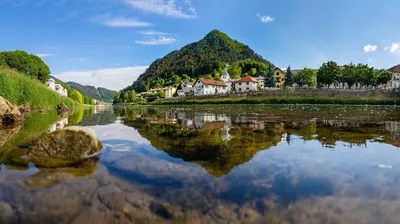 a river with houses and mountains in the background at Hotel Špica Laško in Laško