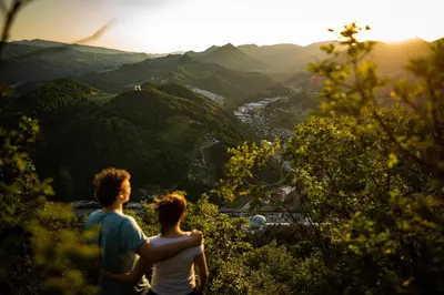 two people standing on top of a hill looking at the mountains at Hotel Špica Laško in Laško