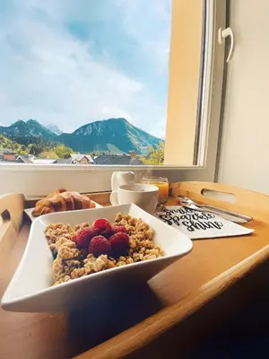 a plate of cereal and berries on a table with a window at Apartment Štros with private sauna in Kranjska Gora