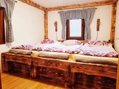 a large wooden bed in a room with a window at RIVER KOLPA APARTMENT, Griblje ob reki Kolpi in Gradac