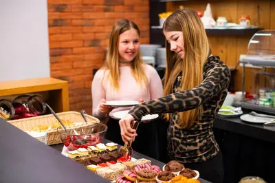 two girls standing in a kitchen preparing food at Pr Anzl in Bled