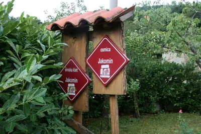 two signs on a wooden post in a garden at Camping Jakomin in Koper
