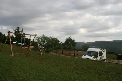 a white van parked in a field with a swing at Camping Jakomin in Koper