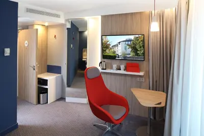 a room with a red chair and a desk at Holiday Inn Express - Ljubljana by IHG in Ljubljana