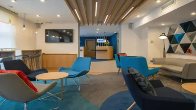 a waiting room with blue chairs and tables at Holiday Inn Express - Ljubljana by IHG in Ljubljana