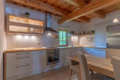 a kitchen with white cabinets and a wooden table at Chalet Haloze in Pristava
