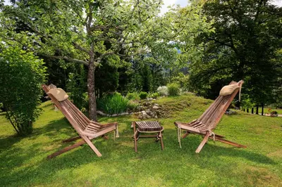 two wooden chairs and a table in a yard at Počitniška hiša ErOs in Bohinj