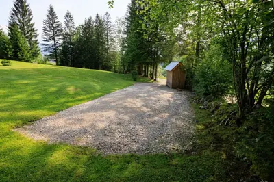 a gravel driveway in a field with a small shed at Počitniška hiša ErOs in Bohinj
