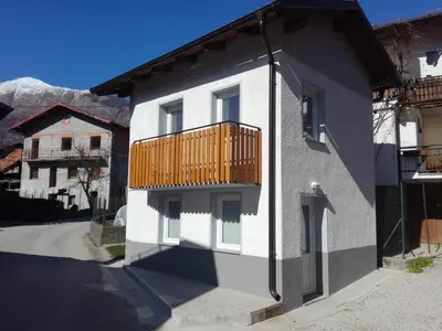 a white building with a wooden balcony on it at Apartma Kambrca in Drežnica
