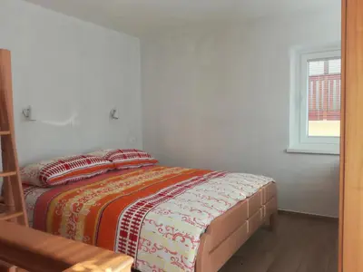 a bed in a white room with a window at Apartma Kambrca in Drežnica