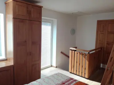 a bedroom with a large window and a wooden closet at Apartma Kambrca in Drežnica
