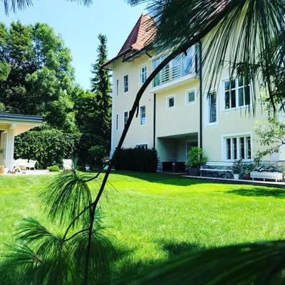 a large white house with a grass yard at Historical Villa in the heart of Bled in Bled