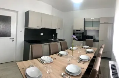 a kitchen with a wooden table with plates and wine glasses at Apartments Andrej - Optuj in Ptuj