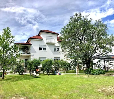 a large white house with trees in front of it at Apartments Andrej - Optuj in Ptuj
