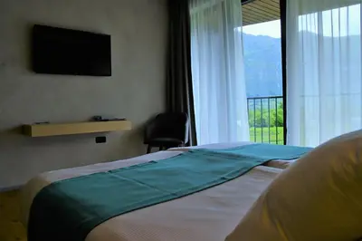 a bedroom with a bed and a window with a television at Hotel Soča in Bovec