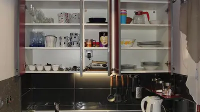 a kitchen with a sink and shelves with dishes at Apartma Tjaša-Terme Čatež in Čatež ob Savi