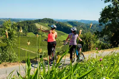 two women riding bikes on a mountain road at Apartma Golob in Zgornja Kungota