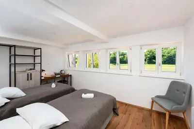 a bedroom with two beds and a chair and windows at Fani&Rozi B&B in Maribor
