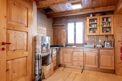 a kitchen with wooden cabinets and a refrigerator at Velika planina Chalet SLOVENKA in Stahovica