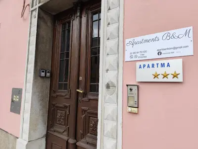a door to a pink building with a sign on it at Apartments B&M in Sežana