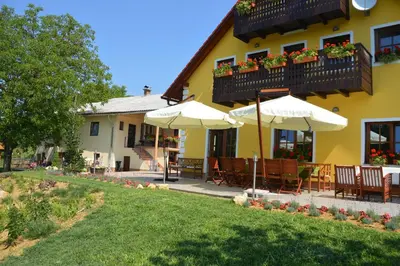 a yellow building with tables and umbrellas in a yard at Hostel Strug in Makole